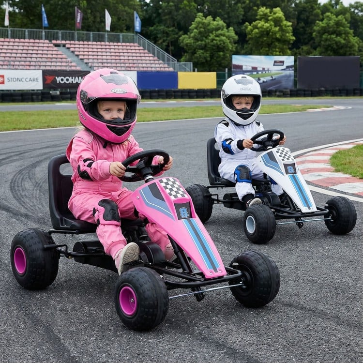 Kids riding pink 4-wheel pedal go-kart with adjustable seat and safe handbrake, perfect for outdoor fun.