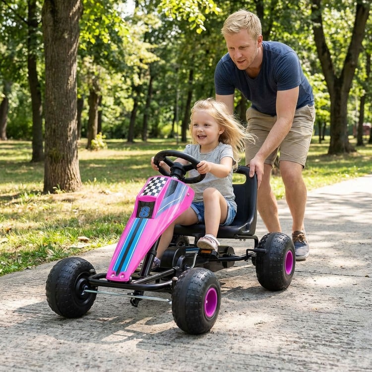 Child riding a pink pedal go-kart with adjustable seat and steering wheel, perfect for outdoor fun and adventure.