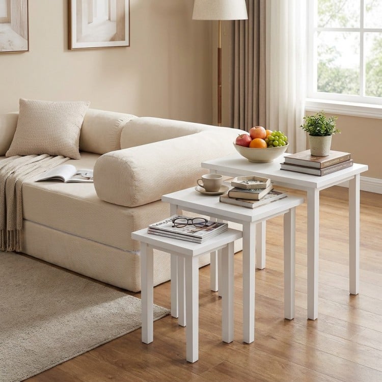 Stackable white side tables with sturdy wood tops beside a convertible sofa bed in a cozy living room setting.
