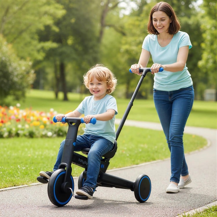 Toddler riding the 4-in-1 foldable tricycle with push handle in a park, featuring adjustable seat and EVA foam wheels.