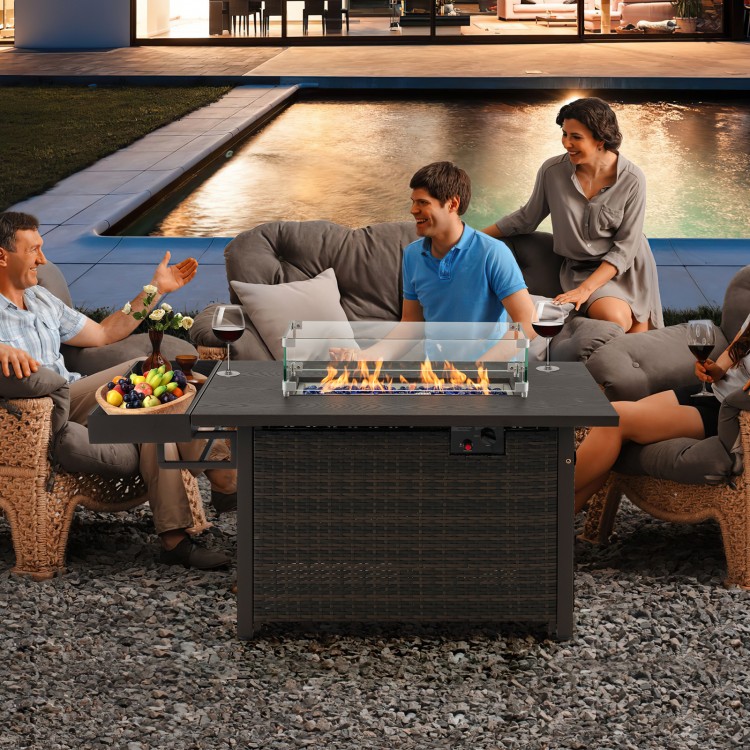 Outdoor wicker gas fire pit table with tempered glass wind guard, 50,000 BTU heat output, perfect for gatherings.