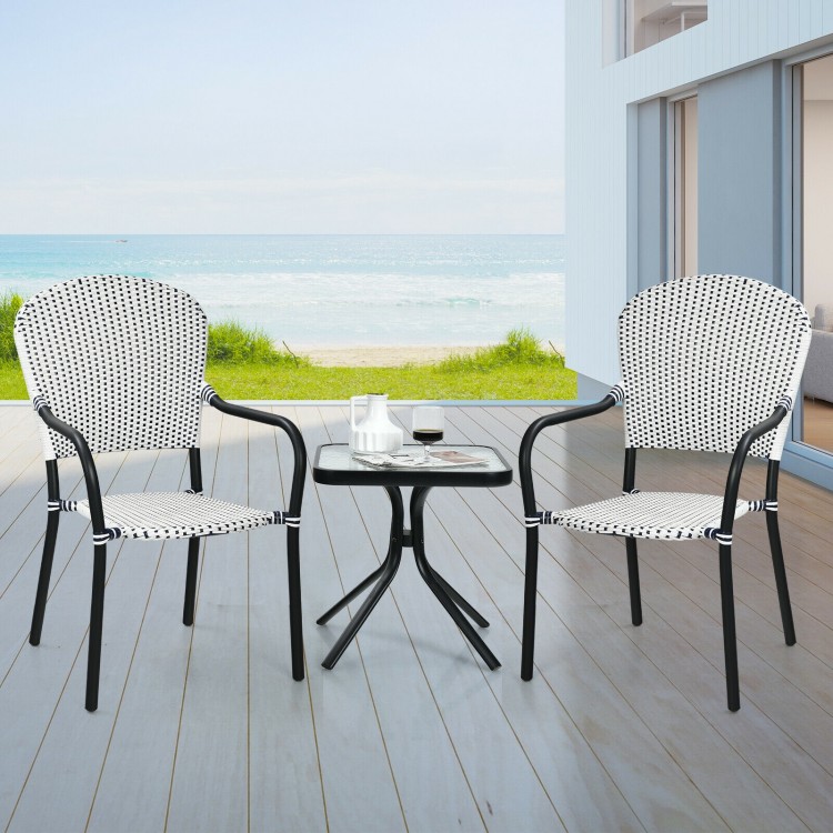 Stackable white rattan dining chairs with armrests, perfect for outdoor use in garden or patio settings.