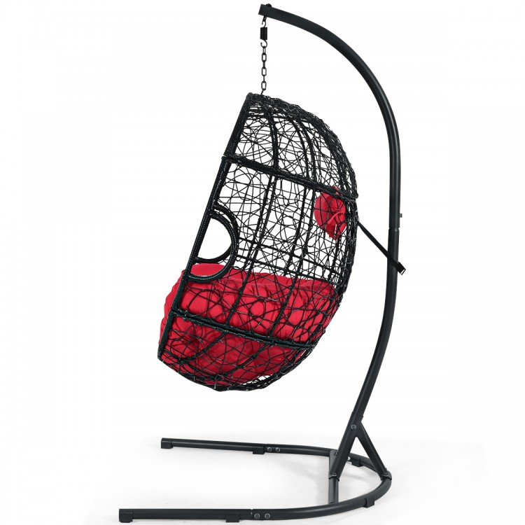 Hanging cushioned hammock chair with stand in red, featuring a sturdy frame and removable pillow for indoor or outdoor.