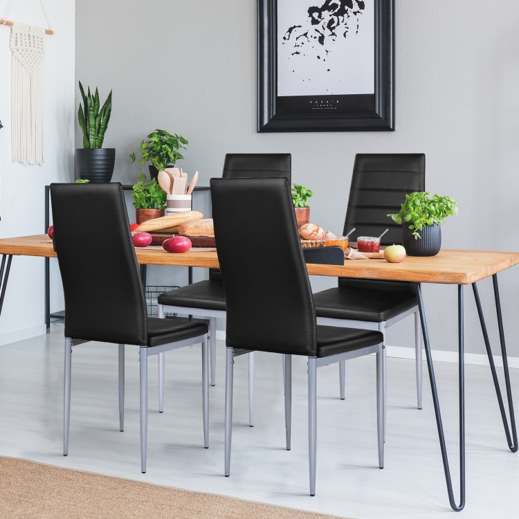 Black PVC leather dining side chairs with painted steel legs, arranged around a modern wooden table in a stylish.
