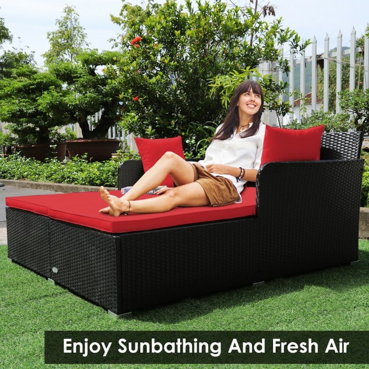 Spacious outdoor rattan daybed with red upholstered cushions, perfect for sunbathing and relaxation in your garden.