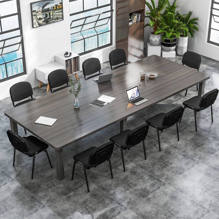 Long conference table with eight black office chairs featuring padded cushions and metal frames, ideal for meetings.