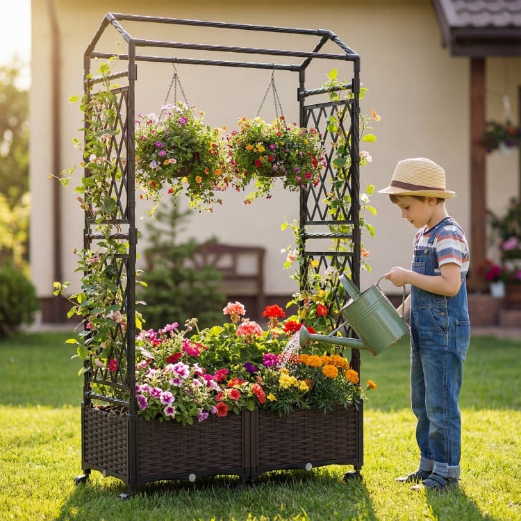 Self-watering planter box with lattice trellis and roof, featuring vibrant flowers and a child watering plants in a.