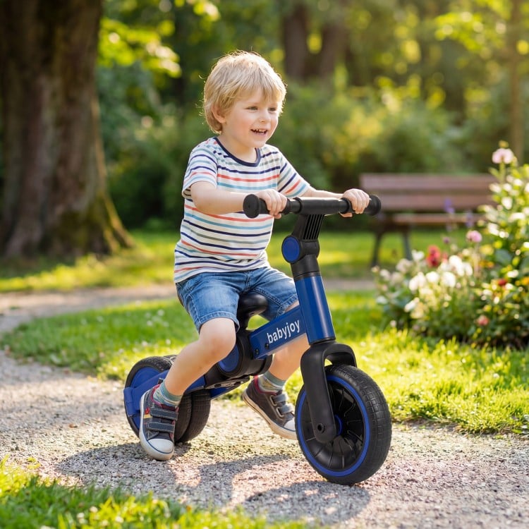 Toddler riding a blue 5-in-1 balance bike with removable pedals in a sunny park, designed for comfort and safety.
