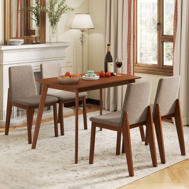 Light brown kitchen table with a smooth surface, complemented by four upholstered chairs, ideal for cozy dining experiences.