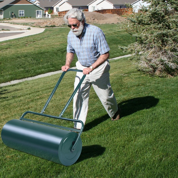 Metal push lawn roller with a green finish, 24 x 13 inches, being used on grass for lawn maintenance.