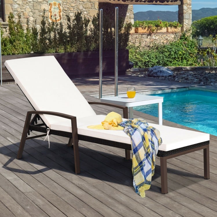 Adjustable back lounge chair with removable white cushion, sturdy rattan design for outdoor relaxation by the pool.