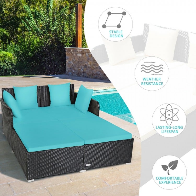 Spacious outdoor rattan daybed in turquoise with upholstered cushions and pillows, perfect for comfortable lounging by.