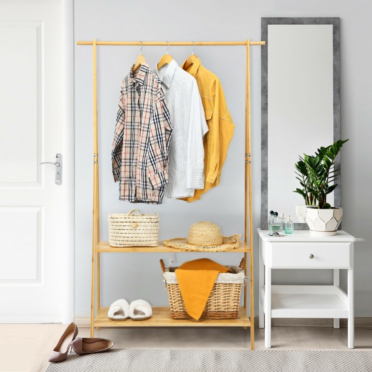 Bamboo clothes hanging rack with a long hanging rod and two shelves, perfect for organizing coats and accessories in.