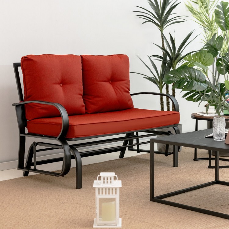 Brick red cushioned patio glider loveseat with ergonomic armrests, perfect for outdoor relaxation in gardens or patios.