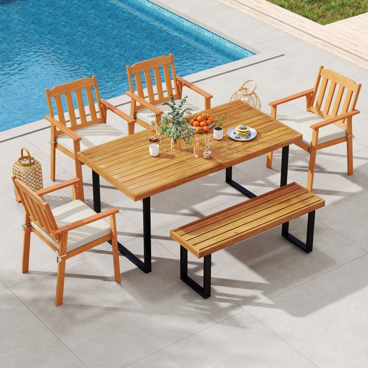 Patio dining set featuring a 63” acacia wood table, four armchairs, and a backless bench for outdoor gatherings.