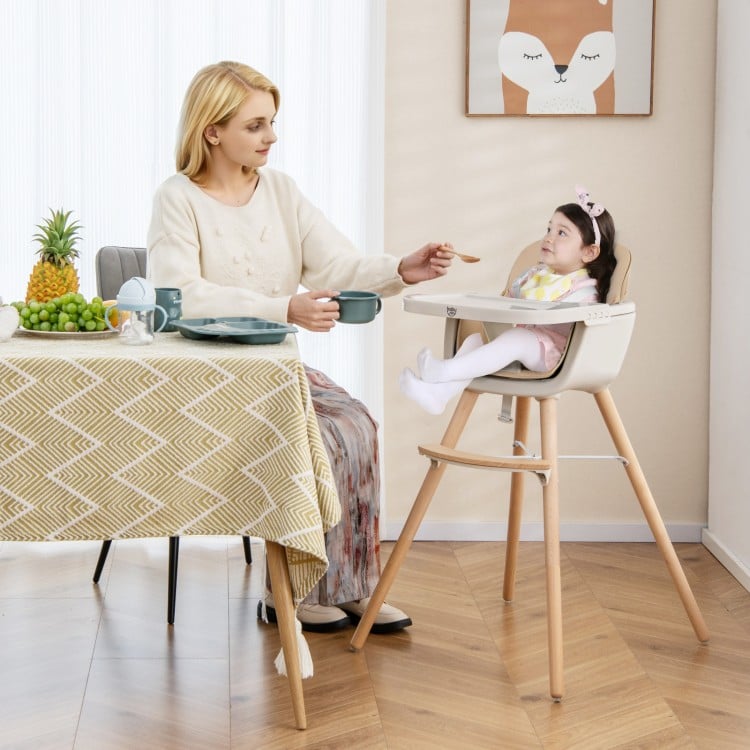Convertible wooden highchair in light brown with safety harness, adjustable legs, and cozy PU cushion for mealtime.