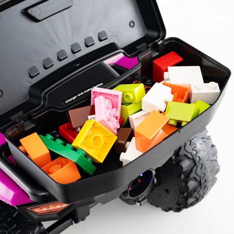 Colorful building blocks stored in the compartment of a pink 6V kids ride-on ATV with music and spray function.