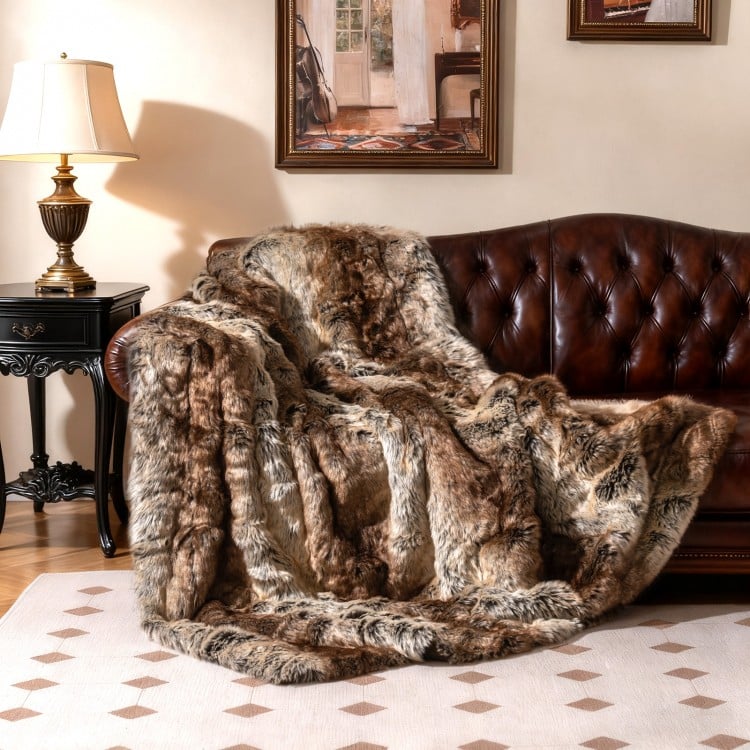 Soft plush fuzzy luxury faux raccoon fur blanket draped over a leather sofa, ideal for cozying up on chilly evenings.