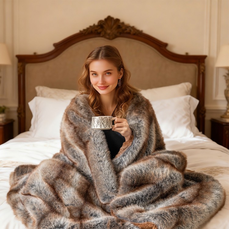 Soft plush fuzzy luxury faux fox fur blanket in brown, draped over a bed, perfect for cozying up with a warm drink.