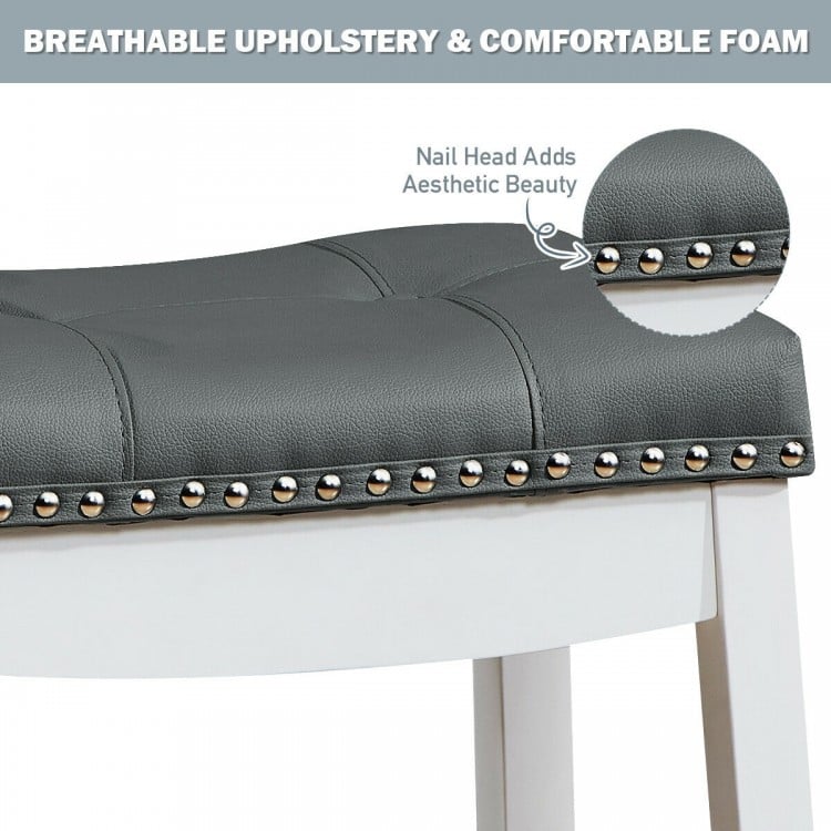 Close-up of the nailhead detail on a gray upholstered saddle bar stool with rubber wood legs for stylish comfort.