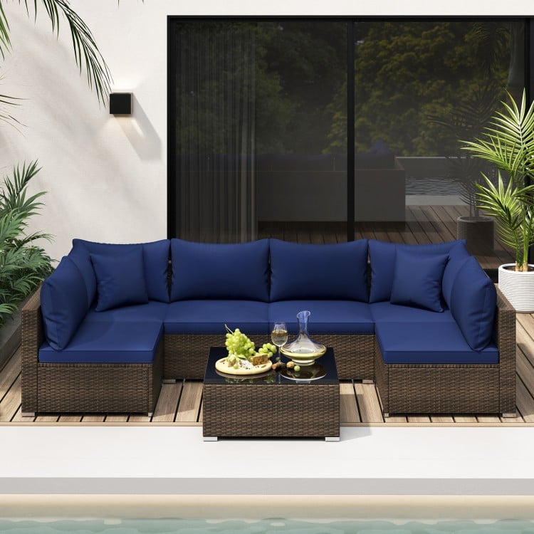 Sectional patio sofa set with navy cushions, featuring PE rattan and a glass coffee table, ideal for outdoor relaxation.