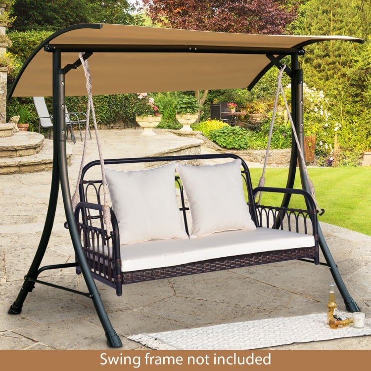 Wicker hanging porch swing with white cushions, designed for outdoor use, supports up to 880 lbs, perfect for gardens.