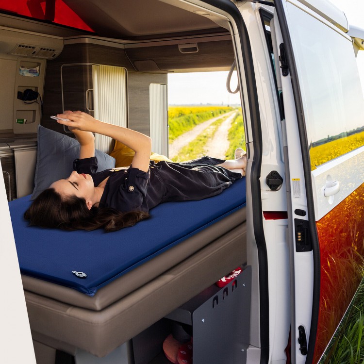 Self-inflating blue foam sleeping cot in a van, designed for comfort with moisture-resistant fabric for outdoor use.