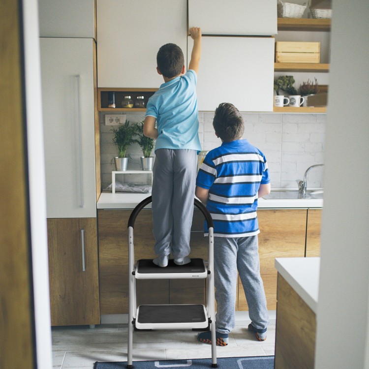 Two children using a 2.75 feet folding step stool with anti-slip pedals for reaching high kitchen cabinets.