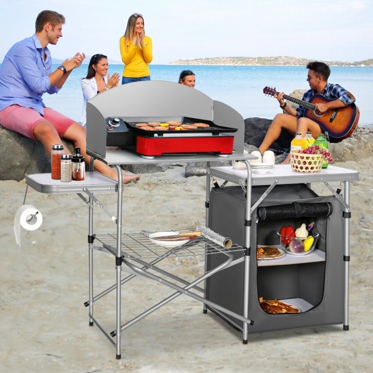 Foldable outdoor BBQ grilling table with windscreen, aluminum frame, and storage bag, ideal for camping and picnics.