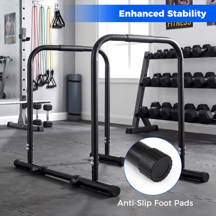 Adjustable dip bar station in black with foam-padded handles and anti-slip foot pads for stable strength training.