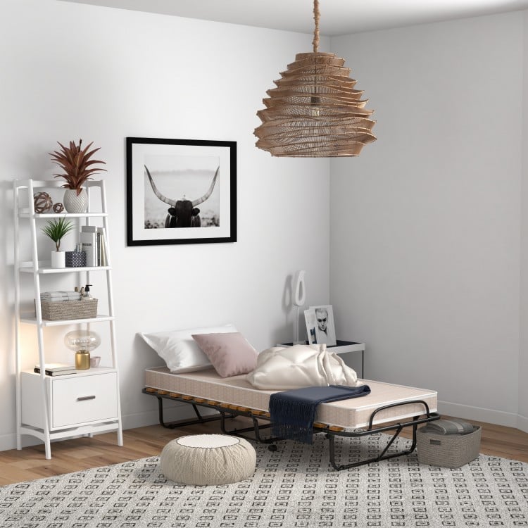 Folding guest bed with memory foam mattress, compact design, placed in a stylish room for versatile use.