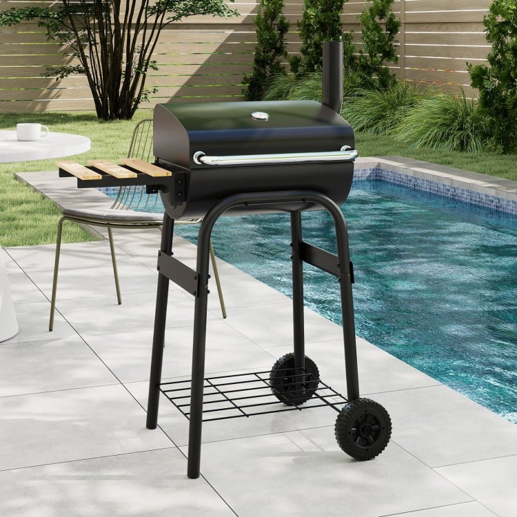 Barrel charcoal grill with foldable side table, built-in thermostat, and wheels for easy transport, perfect for.