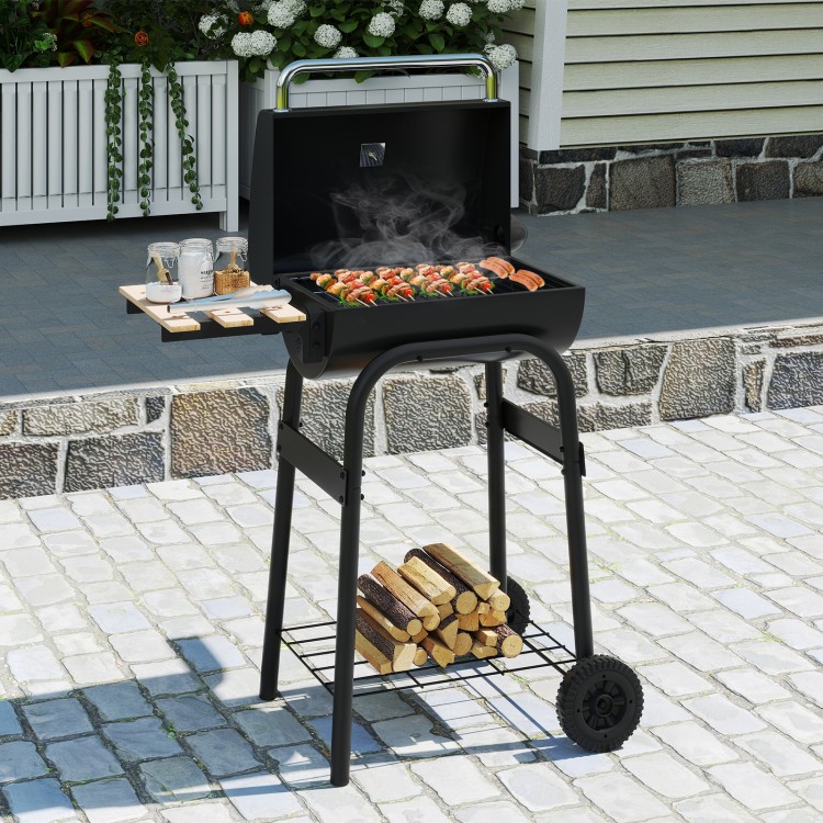 Barrel charcoal grill in black with foldable side table, thermostat, and storage shelf, perfect for backyard cooking.