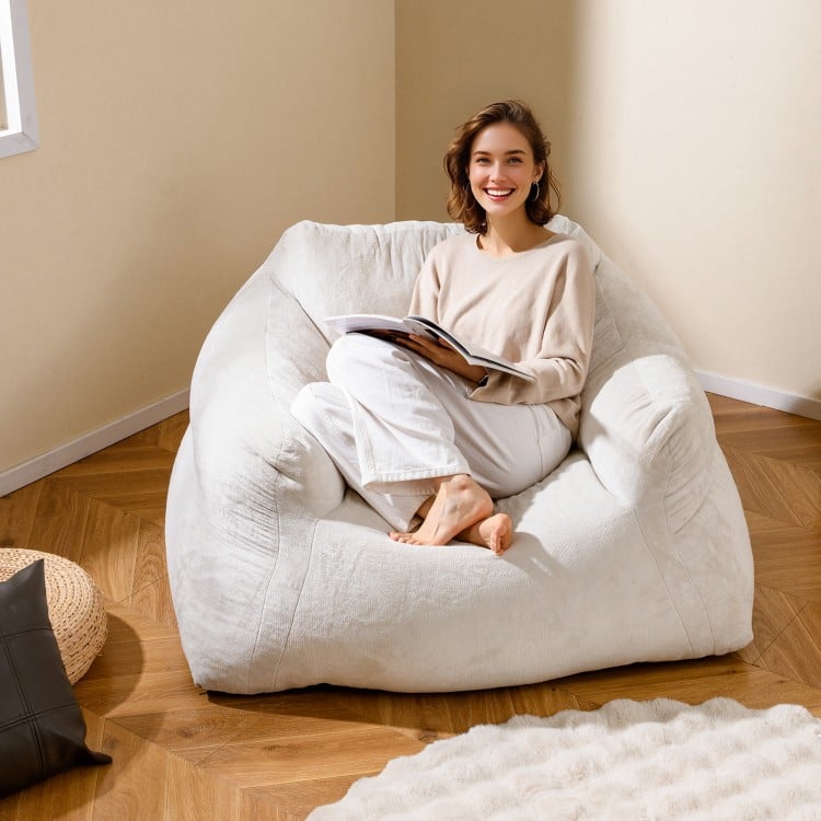 Bean bag chair in beige with plush velvet cover, offering ergonomic support for relaxing and reading comfortably.