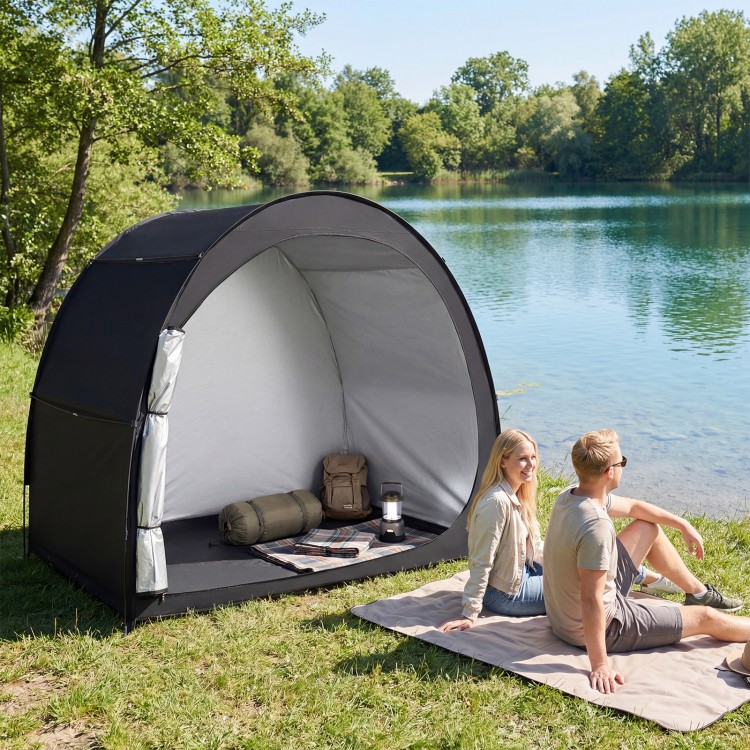 Portable bike storage tent in black with waterproof fabric, set up by a lake for outdoor protection and convenience.