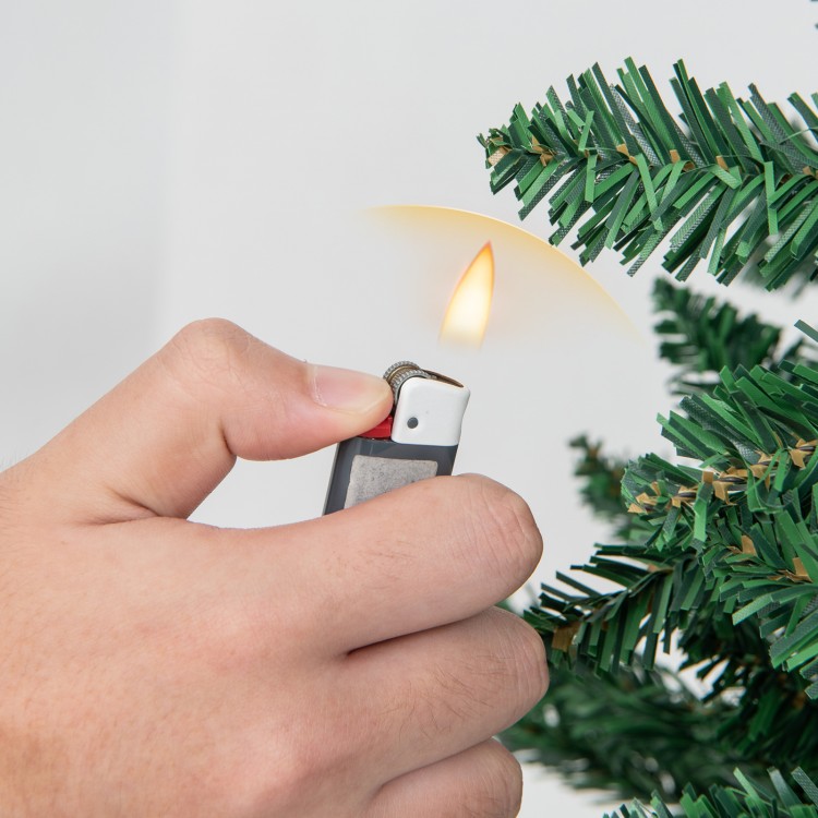 Hand holding a lighter near a 7.5 feet artificial Christmas tree, showcasing its lush PVC branch tips for festive decor.