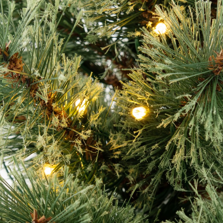 Close-up of flowering pine needles on a 4 feet pre-lit Christmas tree with warm LED lights for festive ambiance.