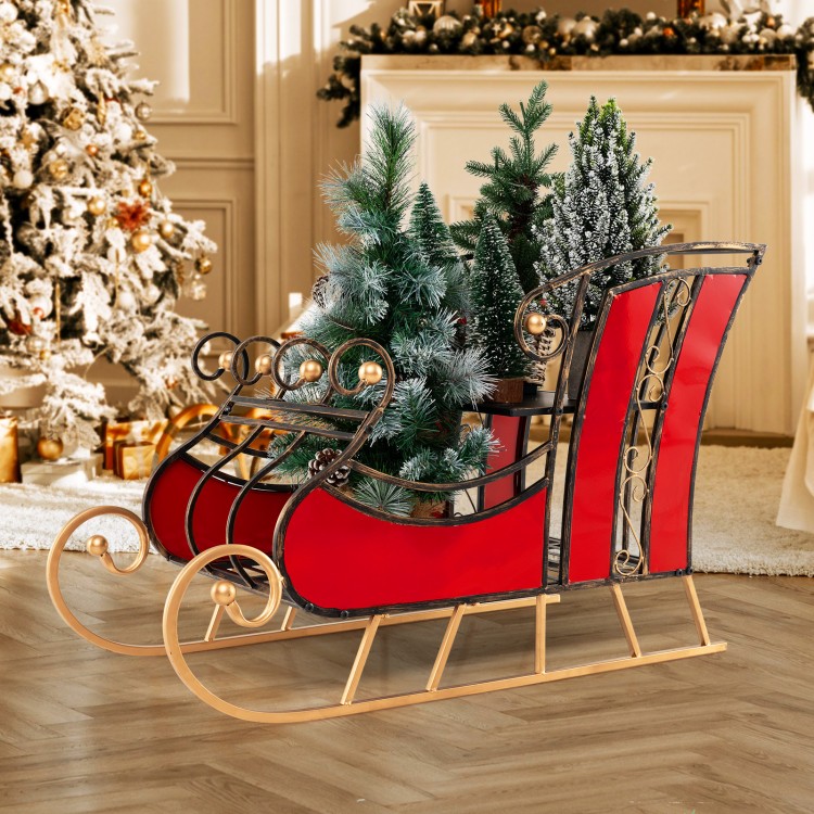 Red metal Christmas sleigh decoration with black and gold scrollwork, featuring a 2-tier storage shelf for festive.