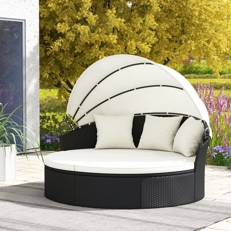 Clamshell patio round daybed in black wicker with retractable canopy and off-white cushions for outdoor relaxation.