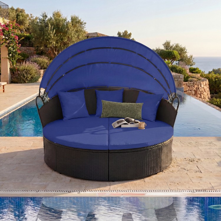 Round blue wicker patio daybed with retractable canopy and pillows, perfect for outdoor relaxation by the pool.