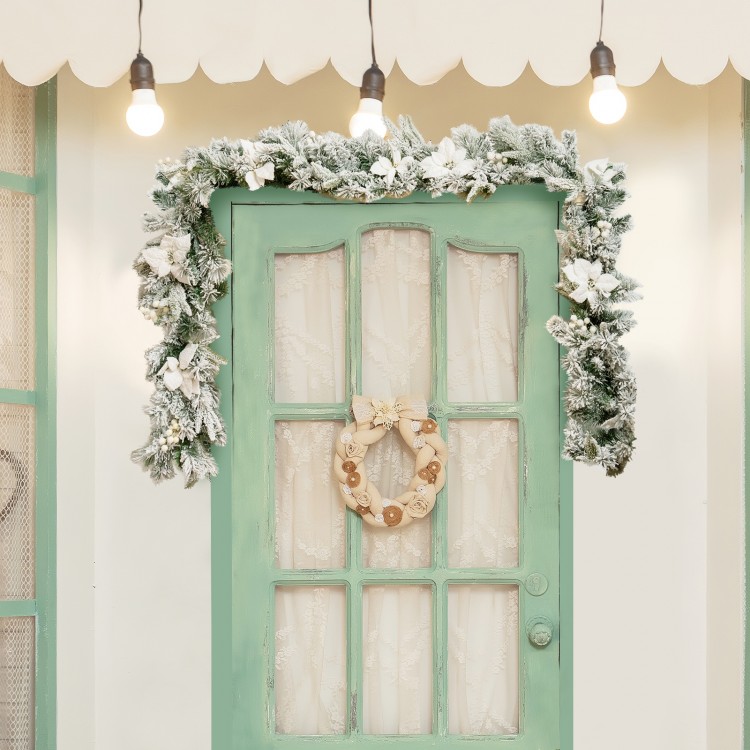 Snow flocked 9 feet pre-lit artificial Christmas garland with 50 LED lights, adorned with white flowers and berries.