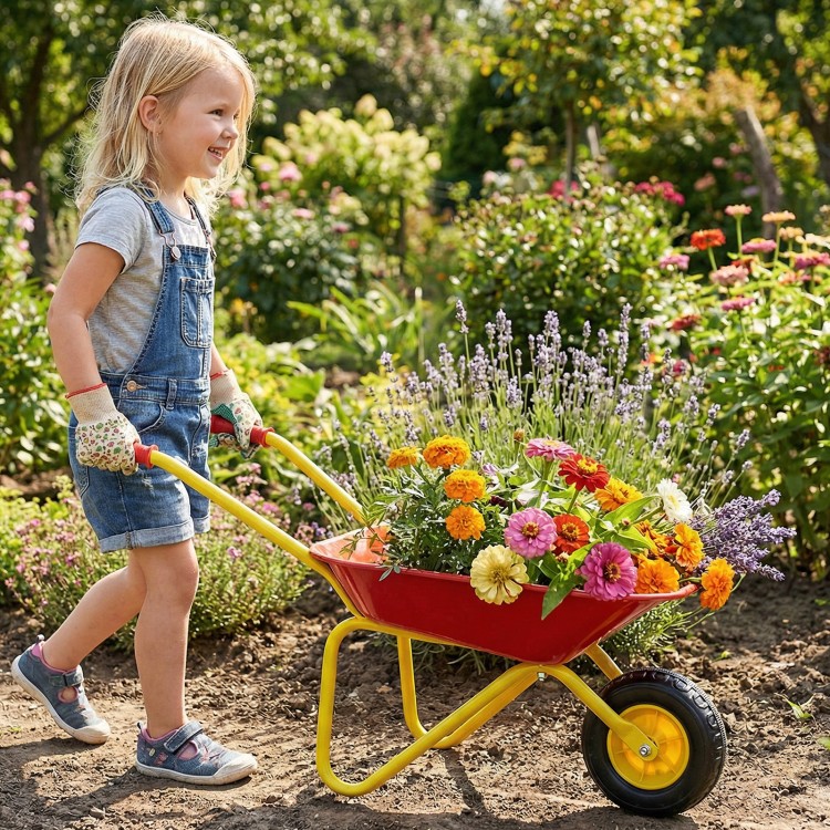 Child pushing a red kids wheelbarrow with flowers, featuring all-terrain wheels for outdoor fun and stability.
