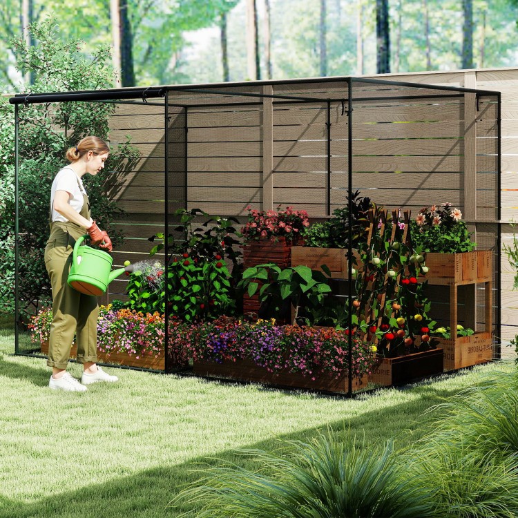 Large crop cage with mesh netting and ground nails, providing plant protection in a garden setting.