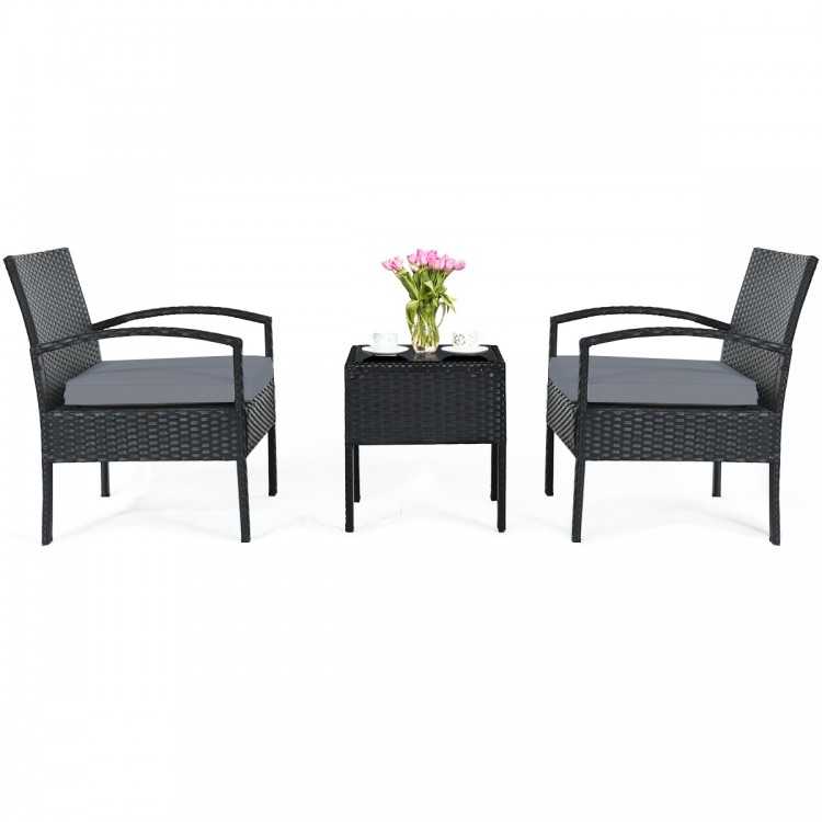 Three-piece outdoor rattan patio conversation set with gray cushions, featuring a tempered glass table, ideal for.