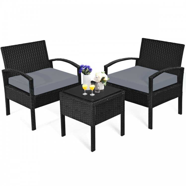 Two black rattan chairs with gray cushions and a glass-top table, perfect for outdoor patio relaxation.