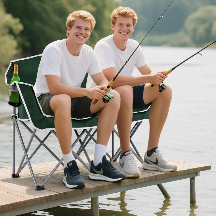 Portable oversized loveseat camping chair in green with armrests and cup holders, perfect for lakeside relaxation.