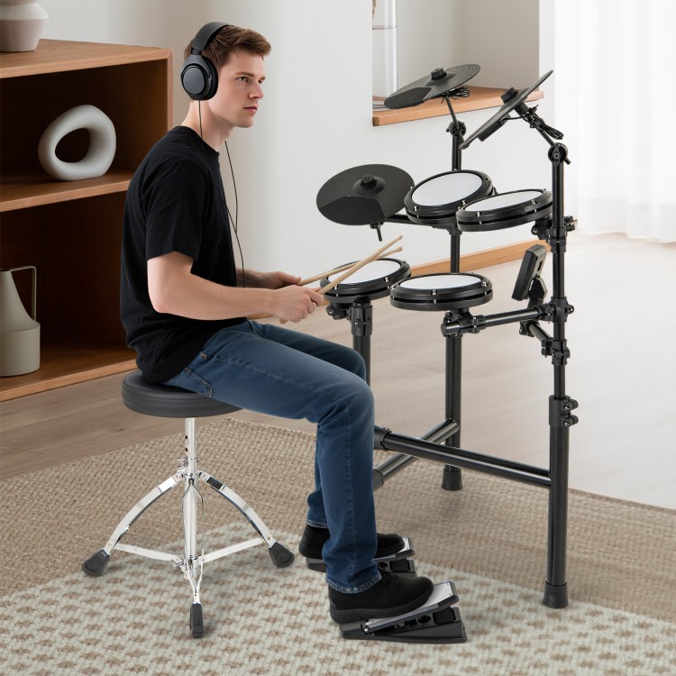 Electric drum set with double-layer mesh pads, adjustable stool, and headphones for silent practice in a modern setting.