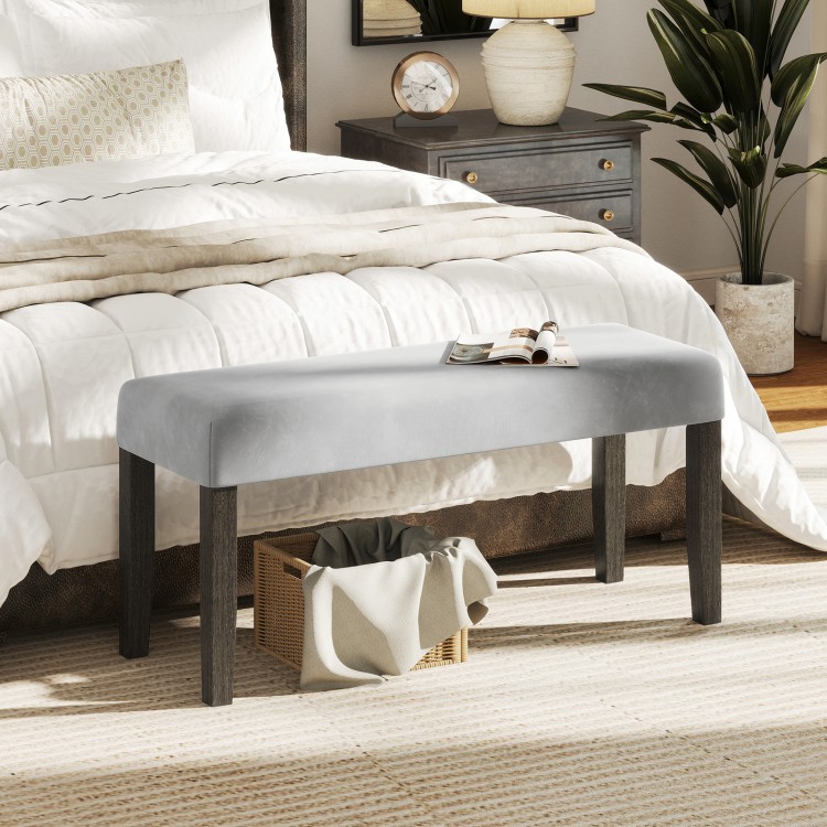 Gray end of bed bench with padded velvet seat and solid wood legs, perfect for bedroom or entryway storage.