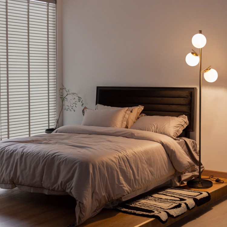 Three-globe floor lamp with golden accents, featuring a foot switch, perfect for stylish corner lighting in any room.