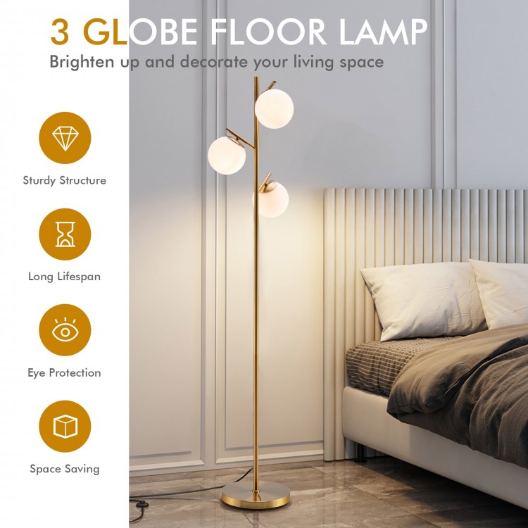 Three-globe floor lamp in gold with glass shades, featuring a foot switch, perfect for stylish corner lighting.